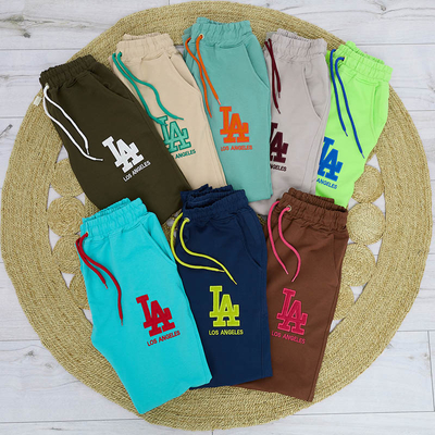 Beżowe damskie spodnie dresowe z kolorową naszywką - Odzież